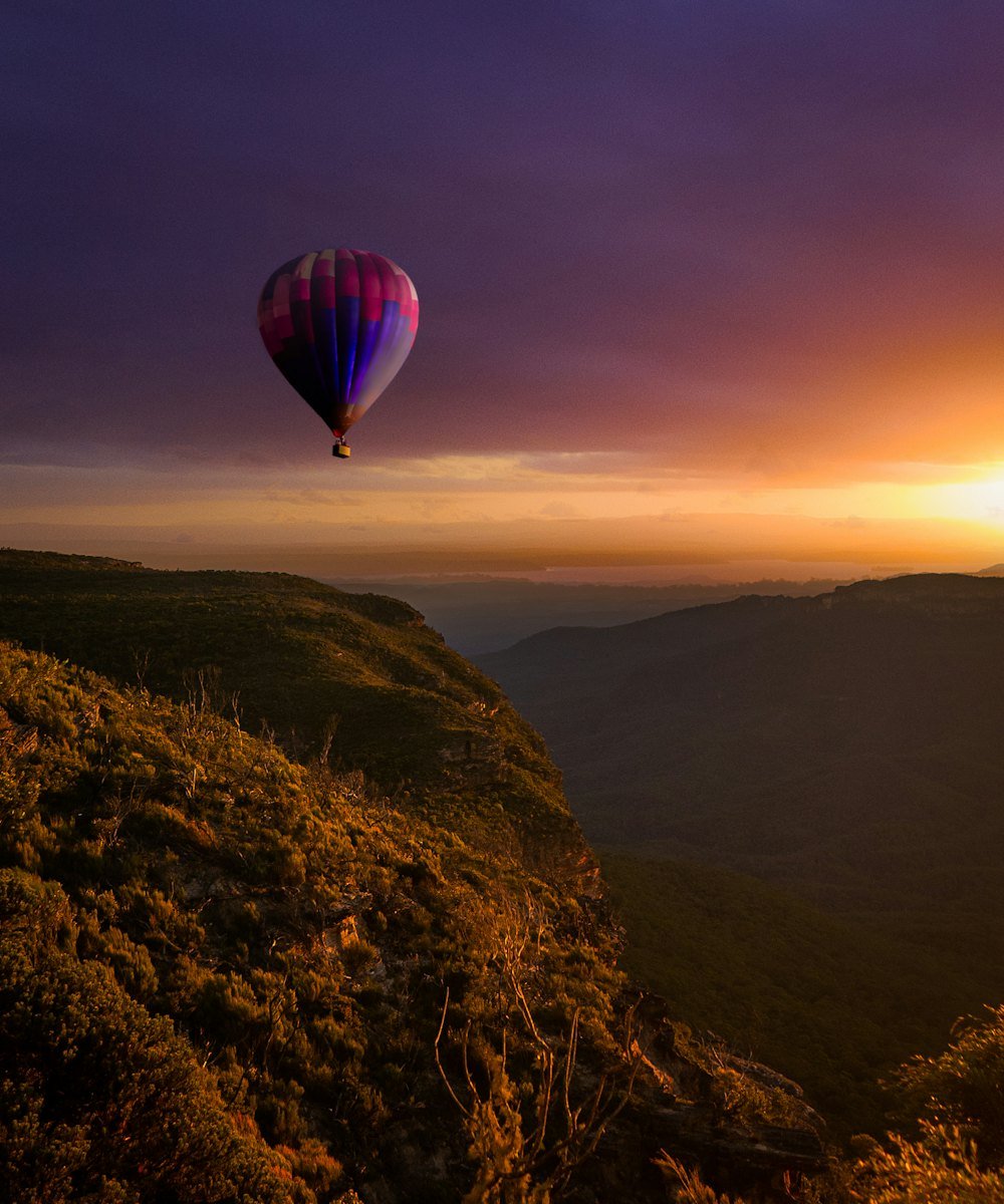 Hot air balloon drifting over mountains at sunset