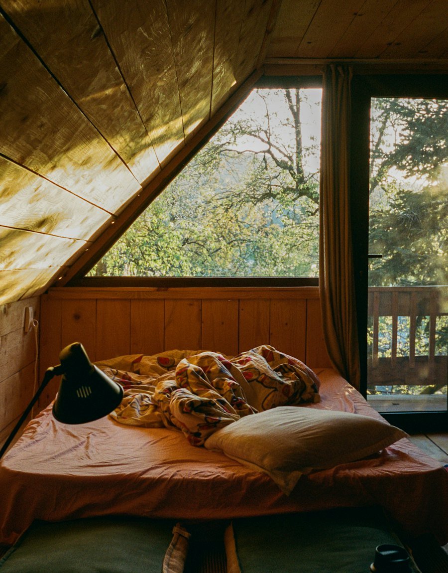 Sunlit attic bedroom with a forest view
