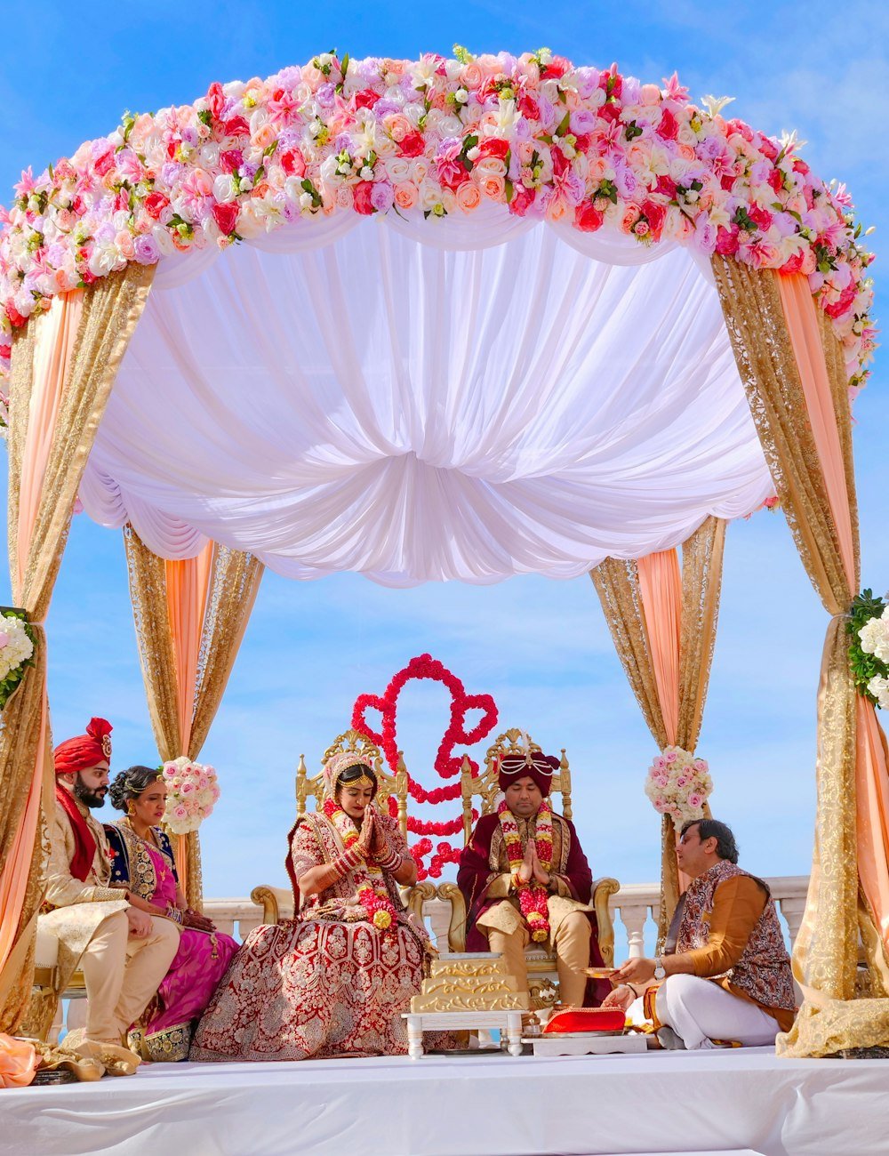 Couple seated under a floral canopy during the ceremony